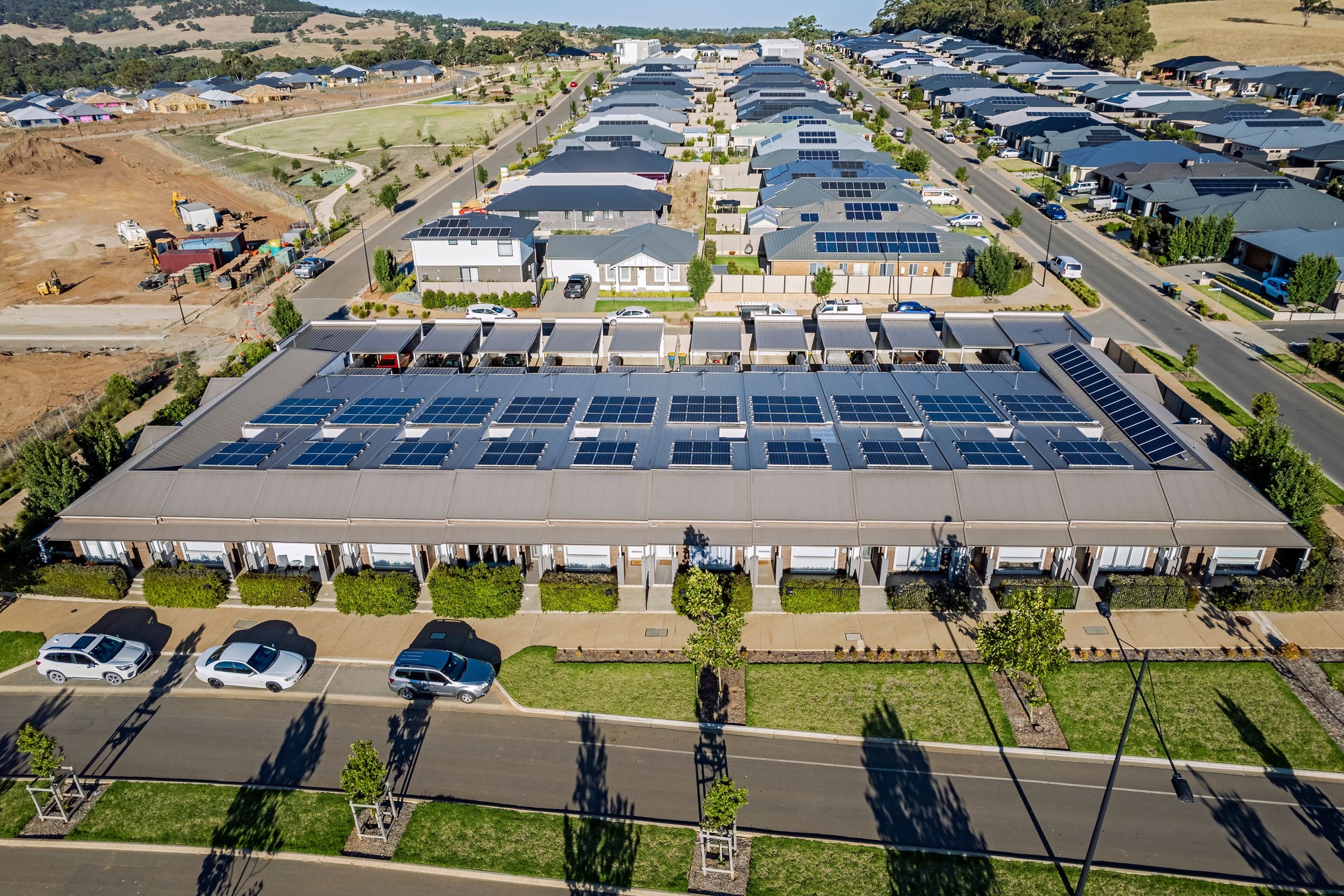 Aerial close view 12 modern narrow houses under one roof with carports at rear of property on new housing development